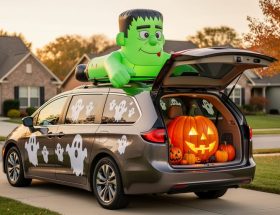 A minivan decorated for Halloween with a Frankenstein roof inflatable, a jack-o’-lantern trunk display, and magnetic ghost decals and window clings.